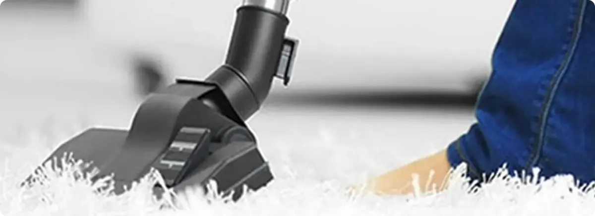 Close-up of a professional vacuuming a white carpet in East Rochester.